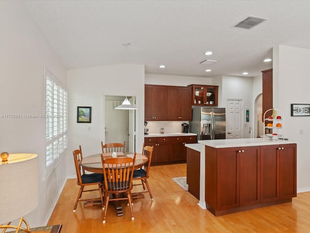 kitchen featuring stainless steel fridge with ice dispenser, decorative light fixtures, and light wood-type flooring