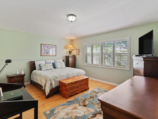 bedroom featuring a textured ceiling and light hardwood / wood-style flooring