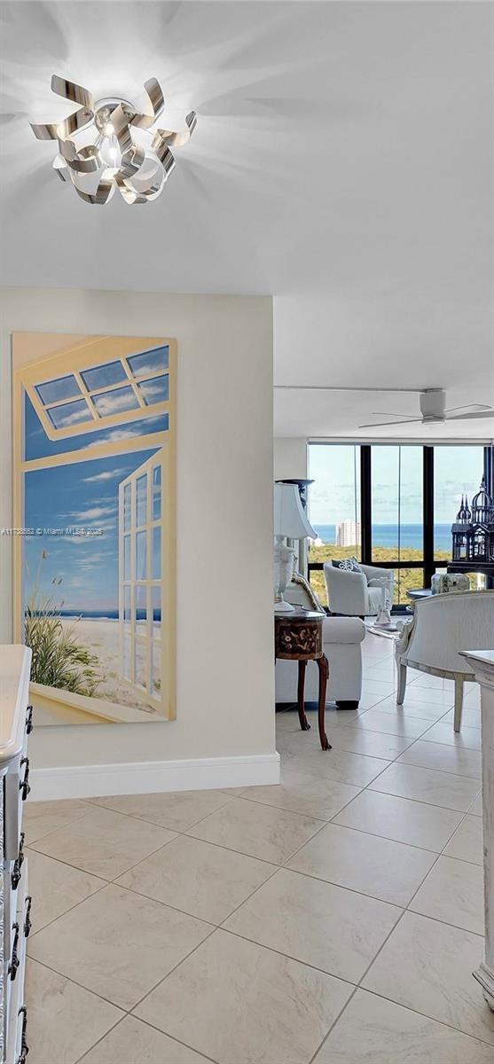 936 Intracoastal Dr Unit 21A, Fort Lauderdale, FL 33304 - corridor featuring an inviting chandelier, a wall of windows, light tile patterned floors, and baseboards