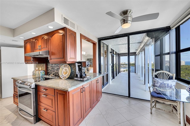 kitchen featuring floor to ceiling windows, light stone counters, stainless steel range with electric stovetop, ceiling fan, and decorative backsplash