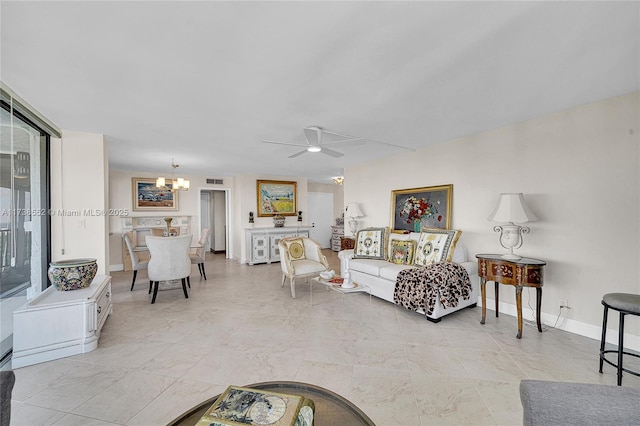 living area with ceiling fan with notable chandelier and baseboards