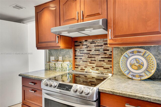 kitchen featuring tasteful backsplash, visible vents, under cabinet range hood, brown cabinets, and electric range