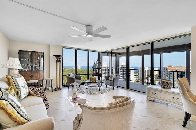 living room with floor to ceiling windows, a water view, light tile patterned floors, and ceiling fan