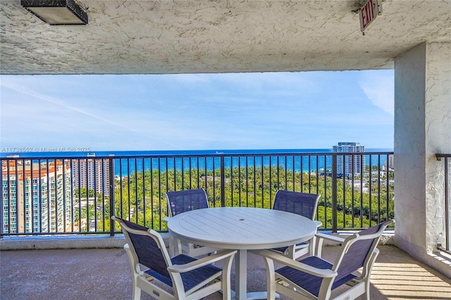 balcony featuring outdoor dining space and a water view