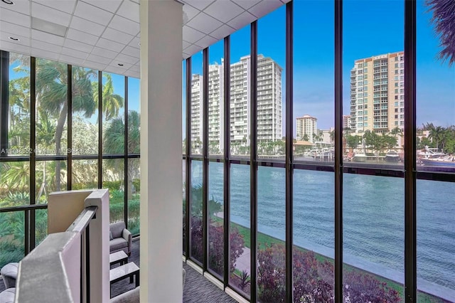 interior space with a city view, a water view, and a drop ceiling