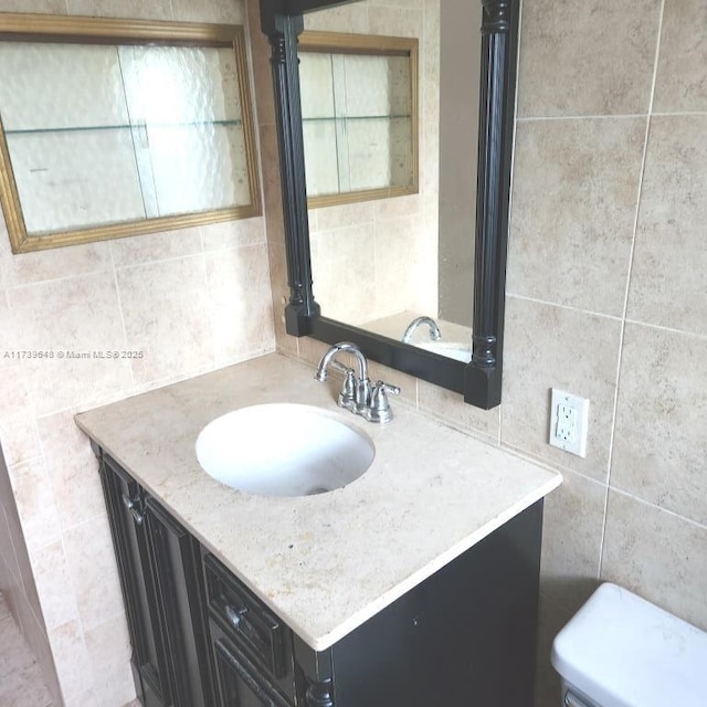 bathroom featuring vanity, tile walls, and toilet