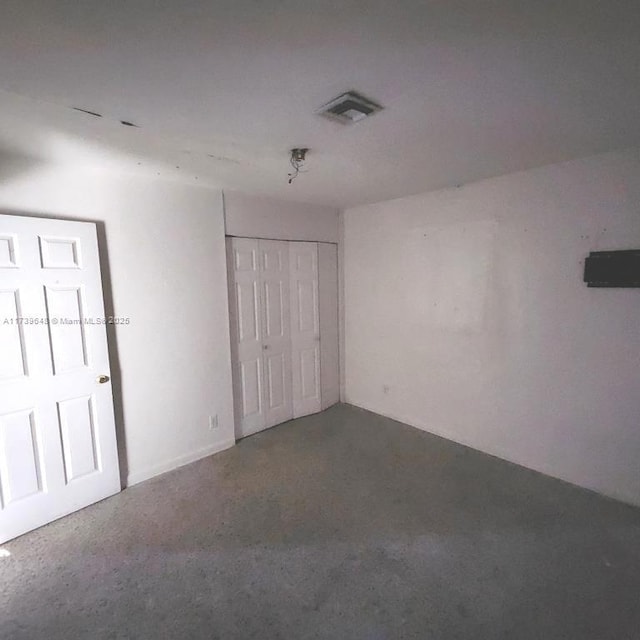 unfurnished bedroom with concrete flooring and a closet