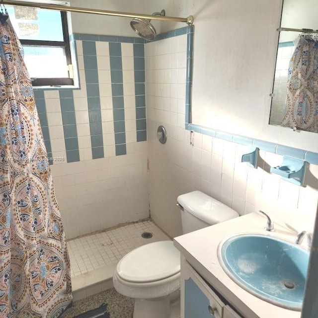 bathroom with vanity, curtained shower, tile walls, and toilet