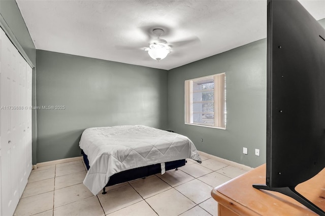 tiled bedroom featuring ceiling fan and a closet