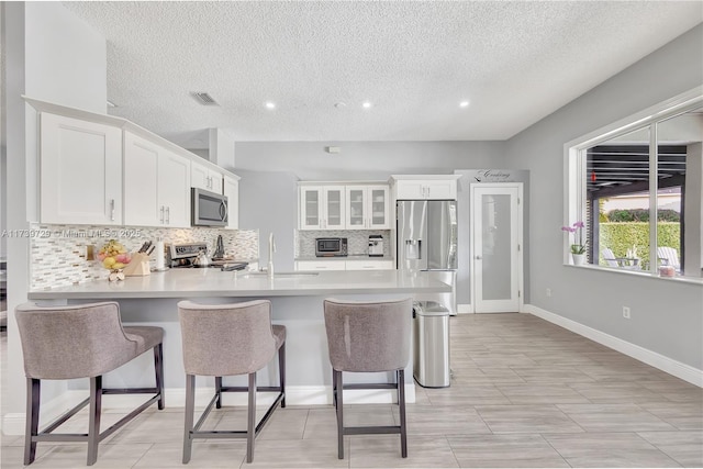 kitchen with sink, a breakfast bar area, appliances with stainless steel finishes, white cabinetry, and kitchen peninsula