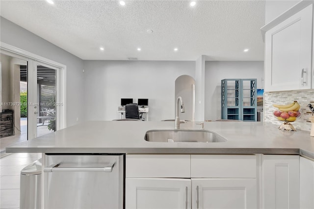 kitchen with a textured ceiling, sink, decorative backsplash, and white cabinets