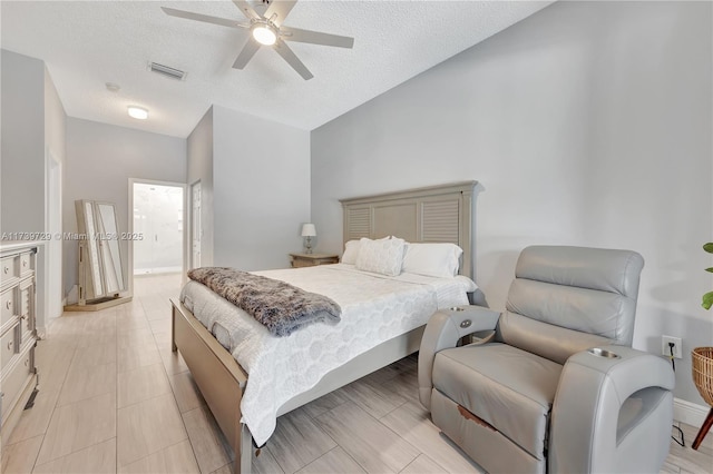 bedroom with ceiling fan, connected bathroom, and a textured ceiling