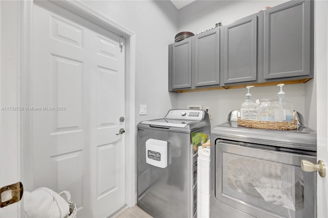 clothes washing area with separate washer and dryer and cabinets