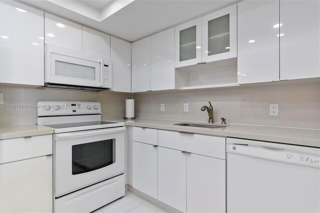 kitchen featuring sink, white appliances, light tile patterned floors, and white cabinets