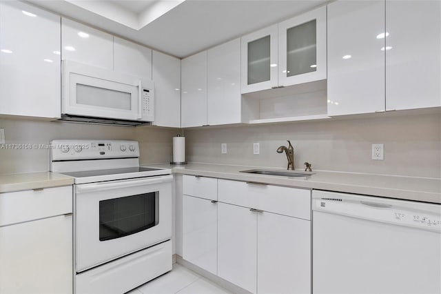 kitchen with sink, white appliances, white cabinets, and light tile patterned flooring