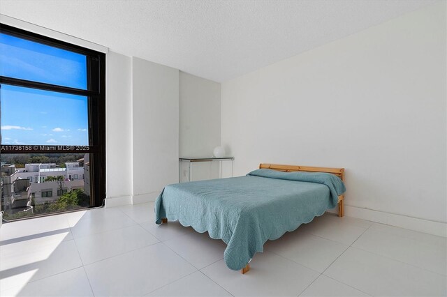 bedroom featuring a wall of windows, a textured ceiling, and light tile patterned floors