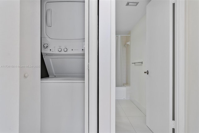 washroom with stacked washer and dryer and light tile patterned floors