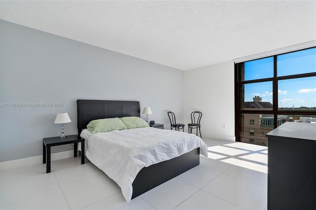 bedroom with expansive windows, light tile patterned floors, and a textured ceiling