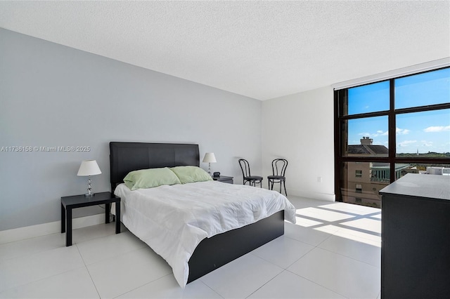 bedroom featuring expansive windows, light tile patterned floors, and a textured ceiling