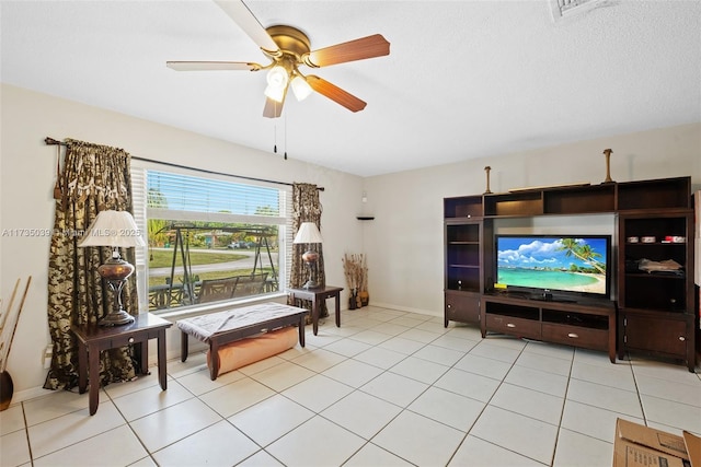 living area with ceiling fan, a textured ceiling, and light tile patterned floors