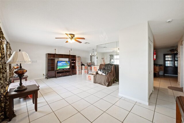 living area featuring baseboards, light tile patterned floors, and ceiling fan