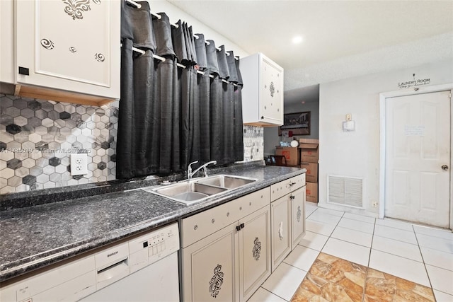 kitchen featuring sink, light tile patterned floors, dishwasher, tasteful backsplash, and dark stone counters