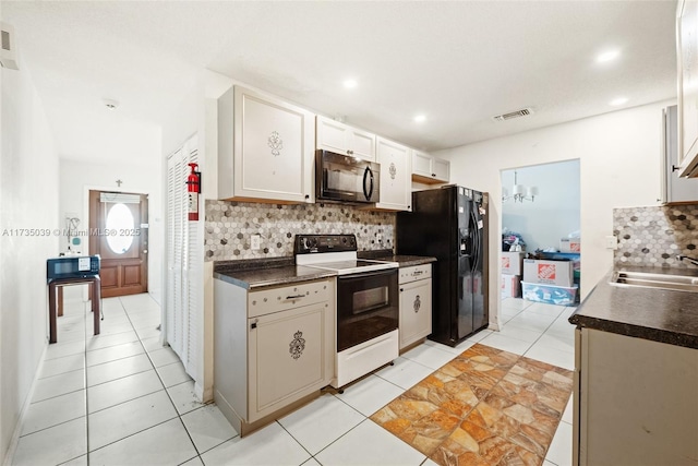 kitchen with a sink, black appliances, visible vents, backsplash, and dark countertops