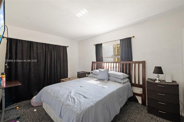 bedroom with dark carpet and a textured ceiling