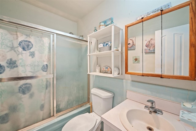 full bathroom with enclosed tub / shower combo, tile walls, vanity, and toilet