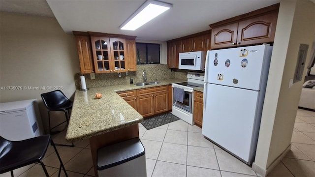 kitchen featuring sink, light stone counters, tasteful backsplash, kitchen peninsula, and white appliances