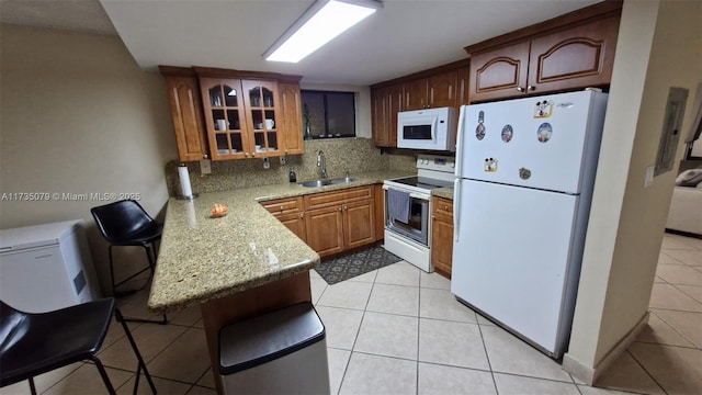 kitchen with sink, light tile patterned floors, white appliances, light stone countertops, and decorative backsplash