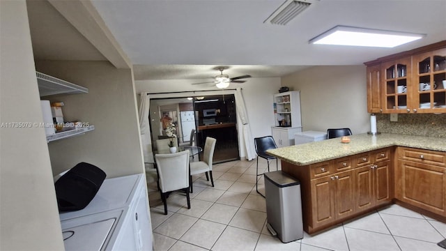 kitchen with light tile patterned floors, backsplash, ceiling fan, and kitchen peninsula