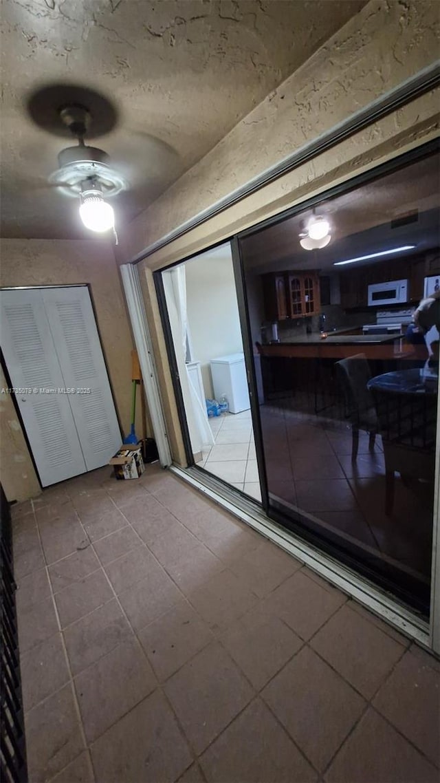 interior space with tile patterned floors and ceiling fan