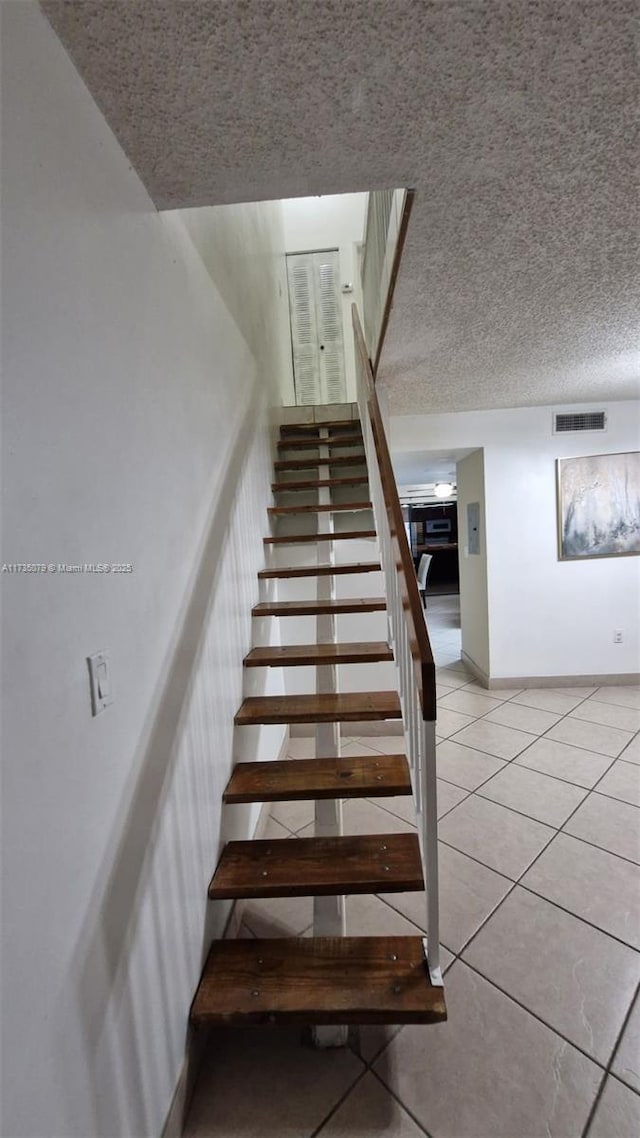 stairs featuring tile patterned floors and a textured ceiling