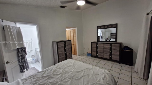 tiled bedroom featuring ensuite bathroom, ceiling fan, and a textured ceiling