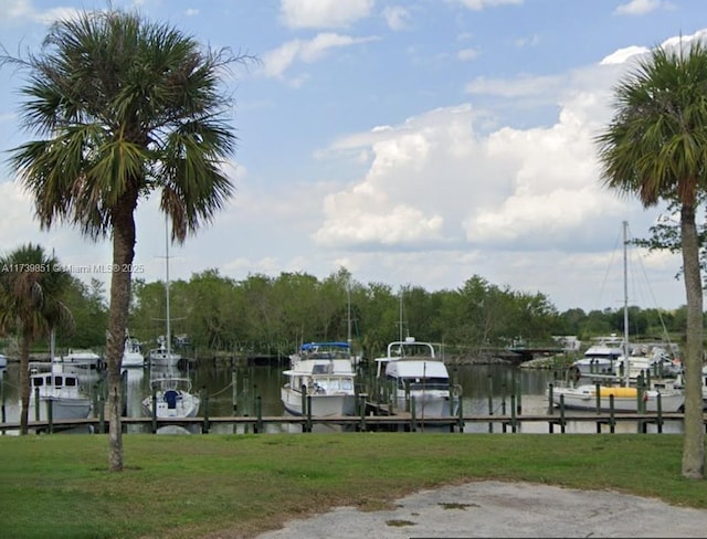 view of dock with a water view, boat lift, and a lawn