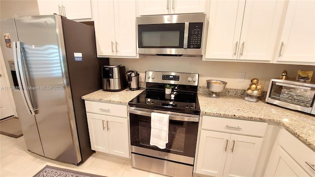 kitchen featuring stainless steel appliances, light stone counters, white cabinetry, and a toaster