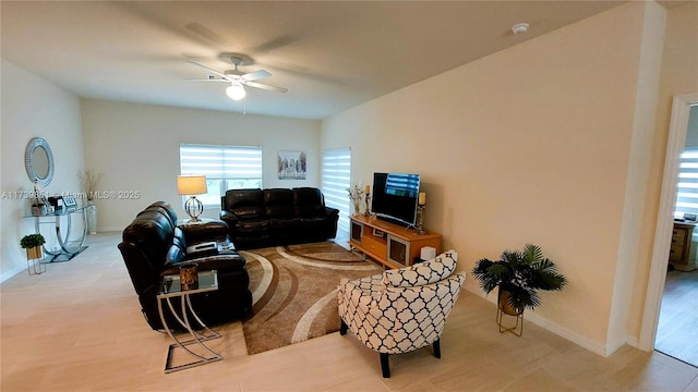 living area with a ceiling fan and baseboards