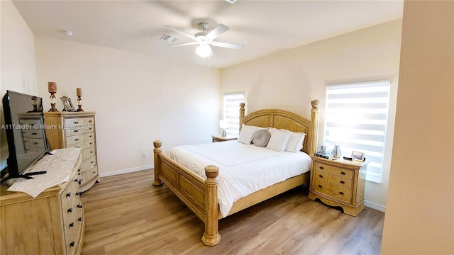 bedroom featuring a ceiling fan, light wood-style flooring, visible vents, and baseboards