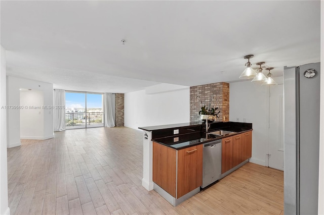 kitchen with appliances with stainless steel finishes, brown cabinets, open floor plan, light wood-type flooring, and a sink