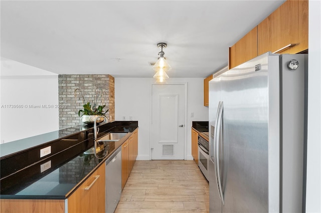 kitchen featuring pendant lighting, light wood finished floors, stainless steel appliances, visible vents, and a sink