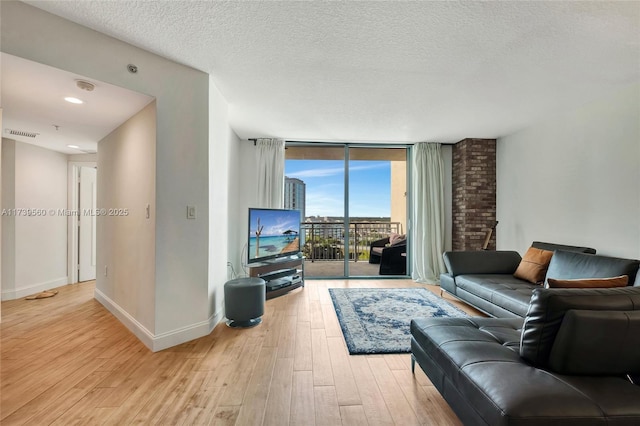 living room featuring floor to ceiling windows, a textured ceiling, and light hardwood / wood-style floors