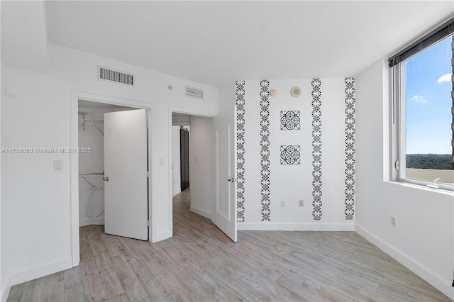 spare room featuring visible vents, light wood-style flooring, and baseboards