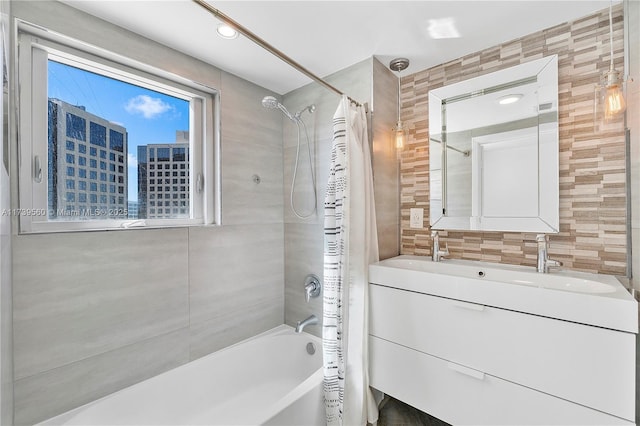 full bath with a city view, tile walls, double vanity, shower / bathtub combination with curtain, and a sink