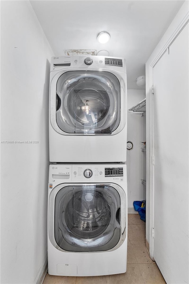 laundry room featuring laundry area, stacked washing maching and dryer, and light tile patterned flooring