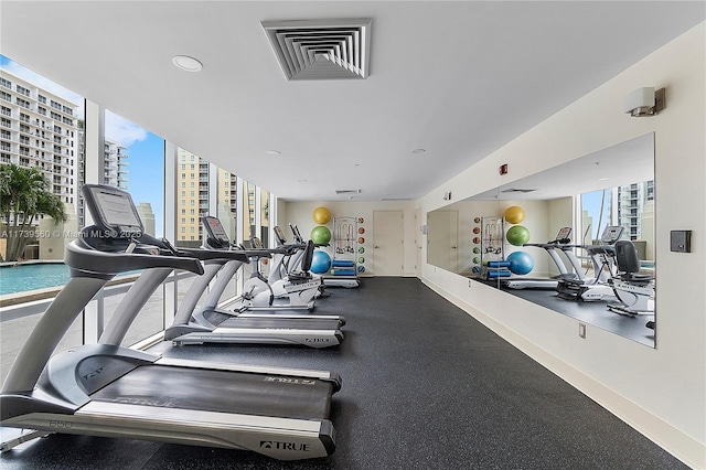 workout area with a view of city, visible vents, a wall of windows, and a wealth of natural light