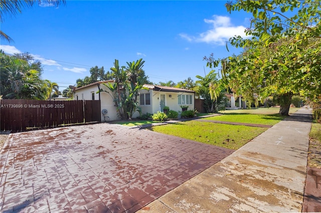 single story home featuring stucco siding, fence, and a front yard