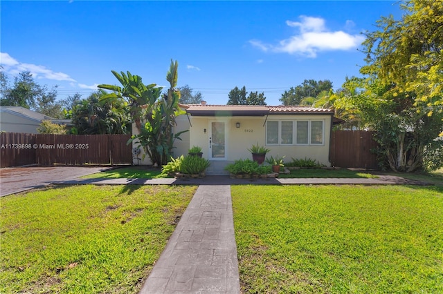 view of front of house with a front yard, fence, and stucco siding