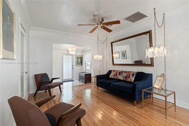 living room featuring baseboards, visible vents, ceiling fan, ornamental molding, and wood finished floors