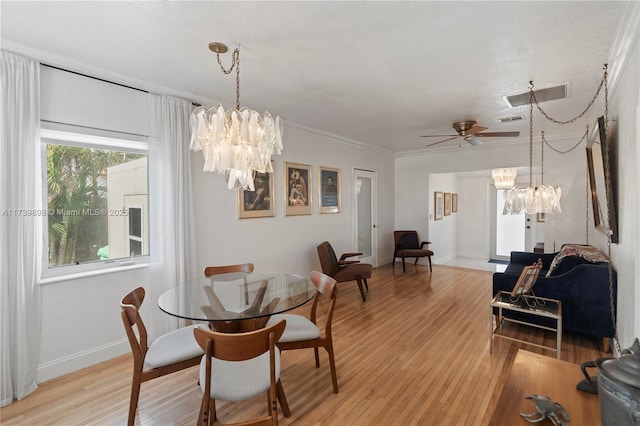 dining space with light wood finished floors, baseboards, visible vents, and ornamental molding